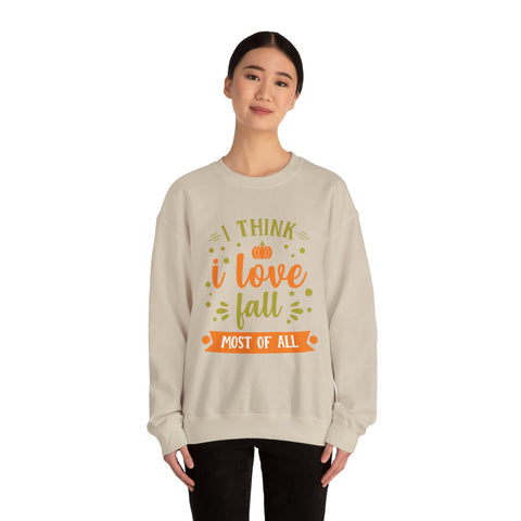 Woman wearing a beige sweatshirt with "I think I love fall most of all" pumpkin graphic.