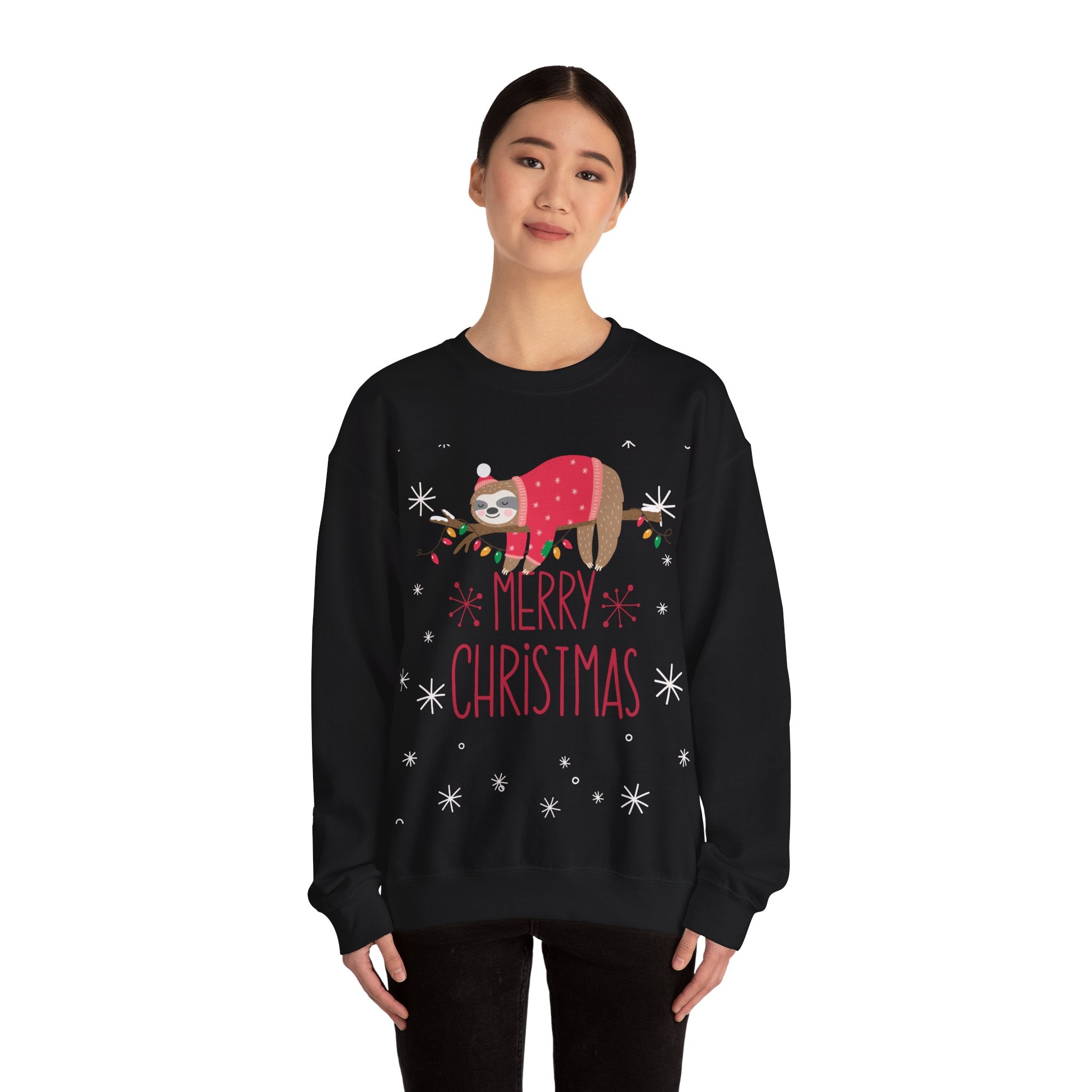 Woman wearing a black 'Merry Christmas' sweatshirt with a sloth wearing a sweater on a branch with lights.