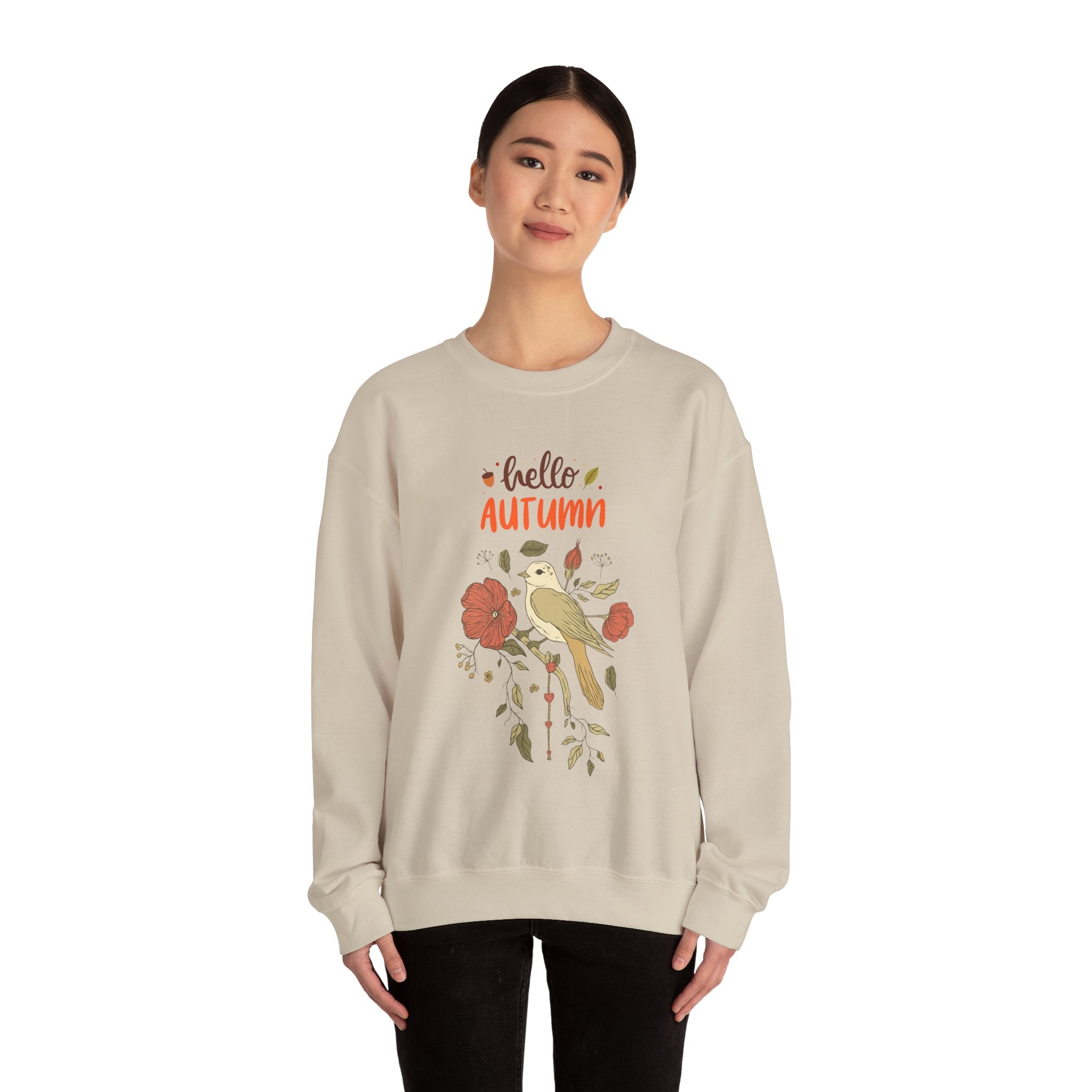 Woman wearing a beige sweatshirt with 'Hello Autumn' and a bird and floral design.