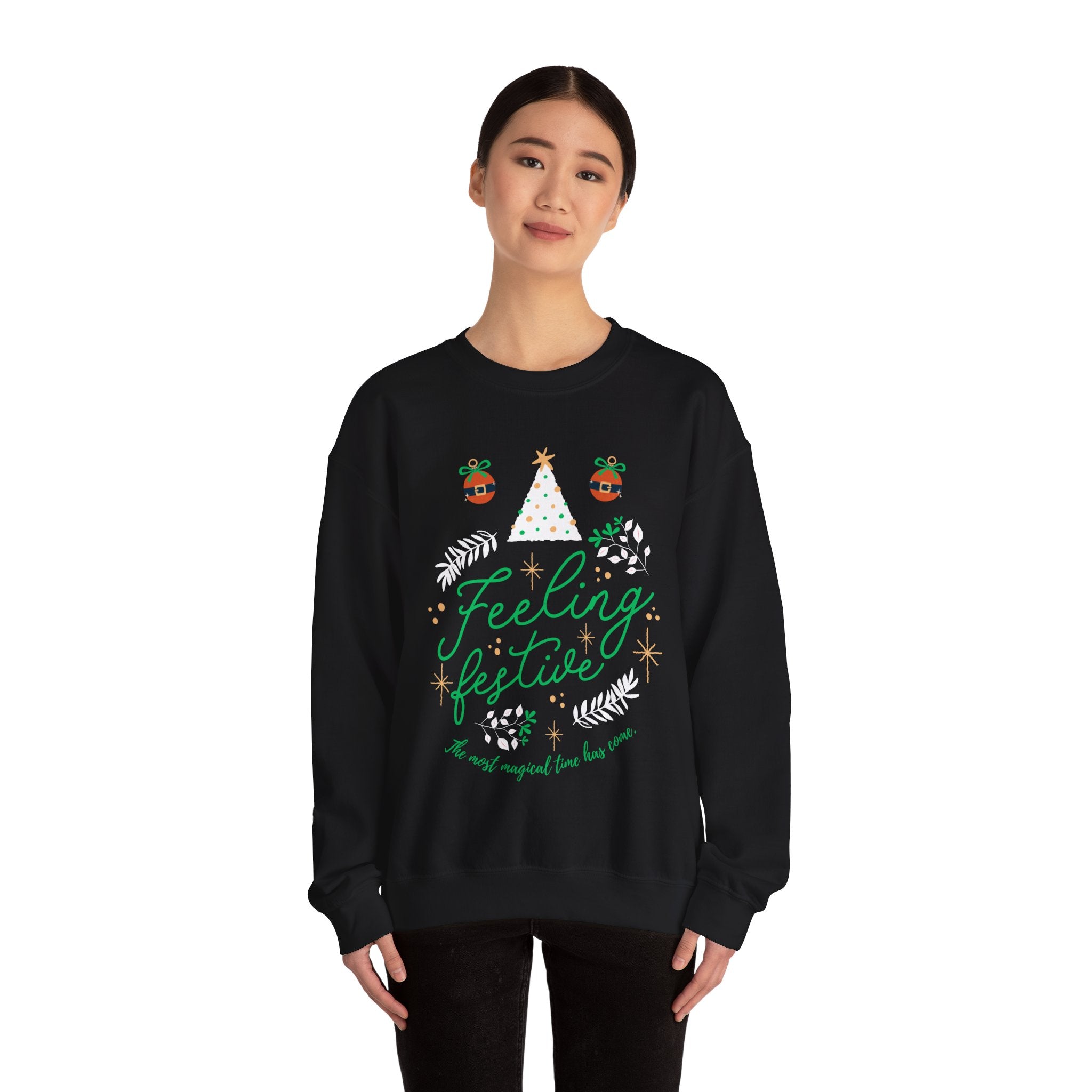 Woman wearing a black 'Feeling Festive' Christmas sweatshirt with tree and ornament graphics.